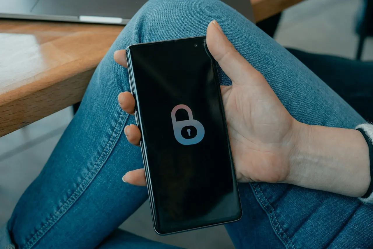 Mão segurando um celular com o ícone de um cadeado na tela